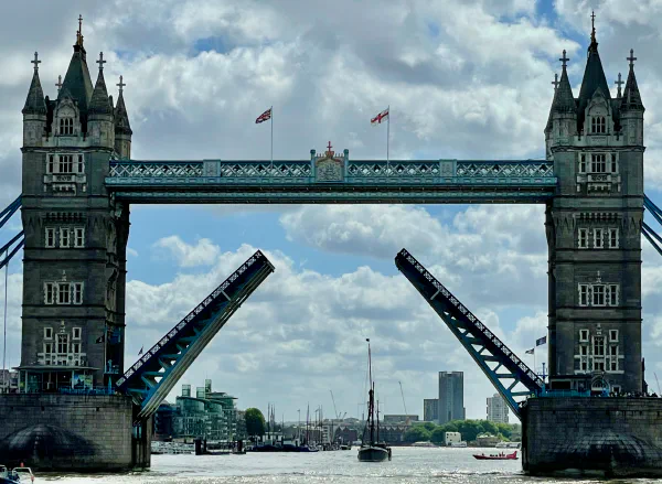 A picture of Tower Bridge in London taken from the Thames facing east. The bridge is open and there's a sailboat just on the far side of the bridge A picture of Tower Bridge in London taken from the Thames facing east. The bridge is open and there's a sailboat just on the far side of the bridge